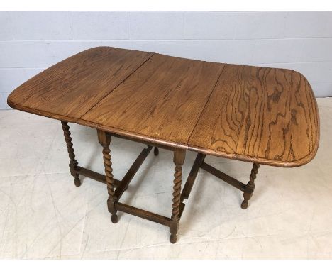 Drop leaf light oak table with turned detailing to legs