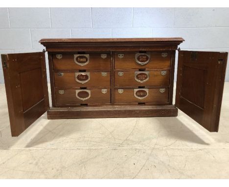 Vintage wooden cabinet with two doors that reveal six drawers with labels