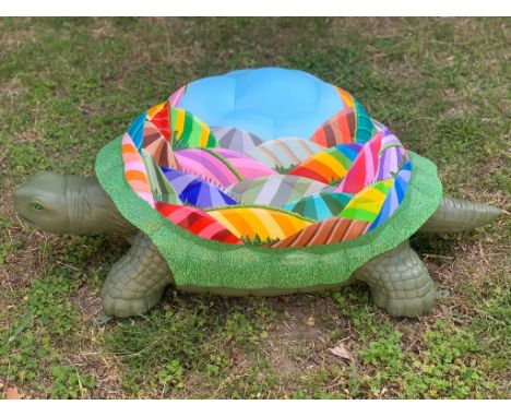 Arcipluvia displays a kaleidoscopic hill scene wrapped around the shell of the tortoise. Arcipluvia means rainbow, and so a R