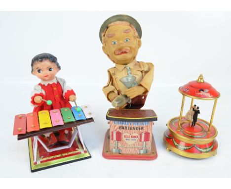 Two tin toys, Charlie Weaver Bartender, a girl playing a xylophone, and a musical ornament of a dancing couple (3). CONDITION