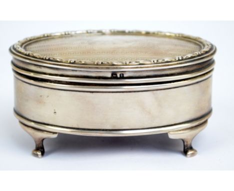 A George V hallmarked silver jewellery box of oval form, centred with a circular vacant cartouche to the hinged engine turned