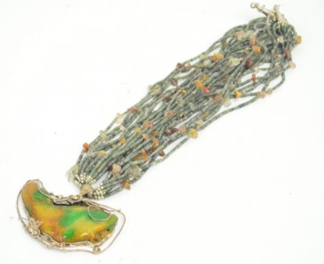 A tricolour jade pendant modelled as a fish with floral sterling silver mounts, suspended on a multi-strand green hardstone a