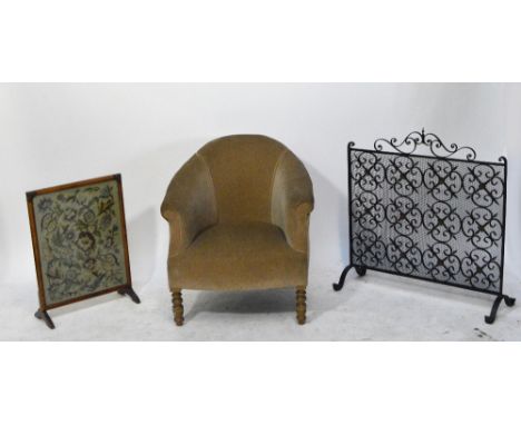 An Edwardian upholstered tub chair raised on turned oak front legs, a walnut framed fire screen and a wrought iron fire scree