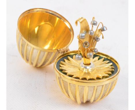An Elizabeth II Silver Jubilee hallmarked silver gilt loaded surprise egg with fluted outside, the hinged lid enclosing flowe
