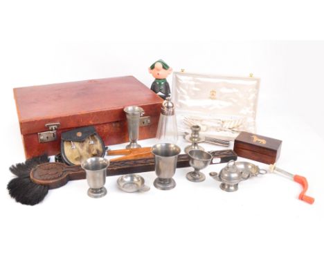 A vintage leather case containing a small quantity of collectibles including a brush with carved oak handle, a pair of nutcra