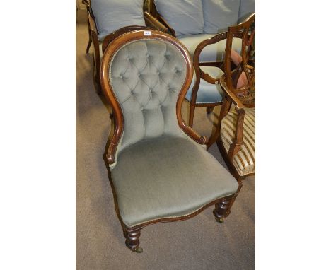 A Victorian mahogany framed spoon back salon chair with button back, on turned front legs to caps and castors. CONDITION REPO