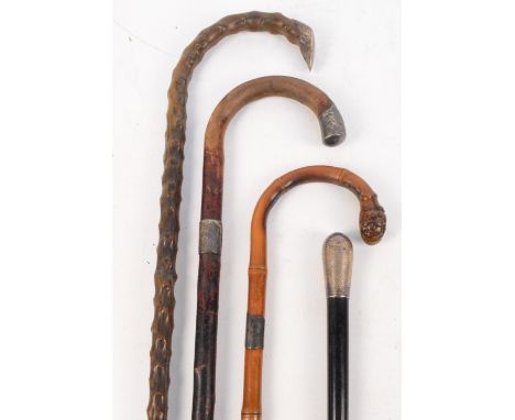 An early 20th century hallmarked silver handled and ebonised walking cane, a bamboo walking stick and two gnarled examples (4