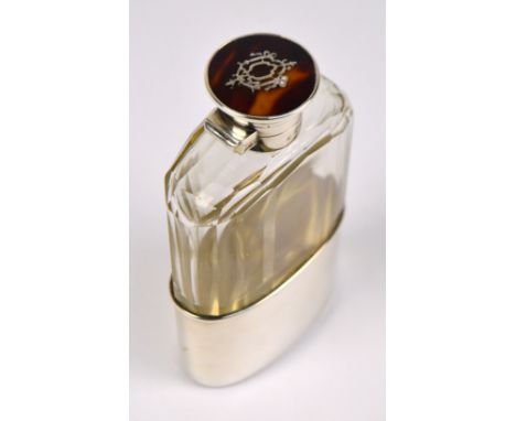 A George V hallmarked silver mounted clear glass hip flask, the hinged screw cap set with pique decorated tortoiseshell round