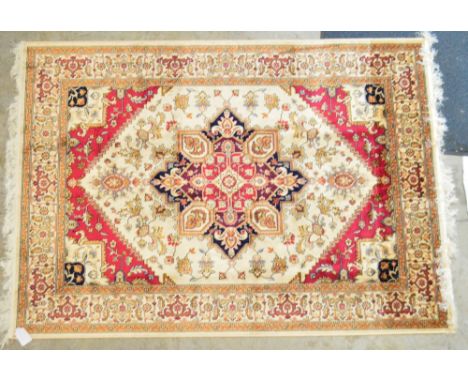 A beige ground Heriz carpet with central geometric floral device with a foliate border, 190 x 140cm.