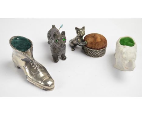 A group of novelty pin cushions comprising a metal scotty dog with green glass eyes, length 75.cm, a metal boot, an example i