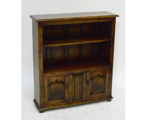 A reproduction oak bookcase, the upper open section set with a single shelf above two fielded panel doors to stile feet, purc