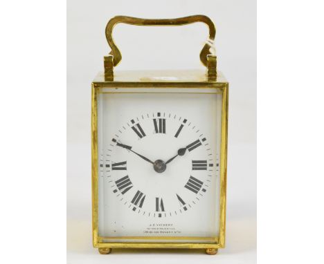 An early 20th century French brass cased carriage clock with swing loop handle above rectangular white enamel dial set with R