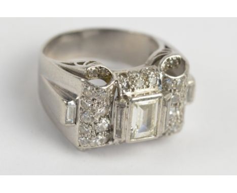 A white metal diamond cluster ring, the central emerald cut diamond weighing approx. 0.70ct flanked by twin further thin bagu