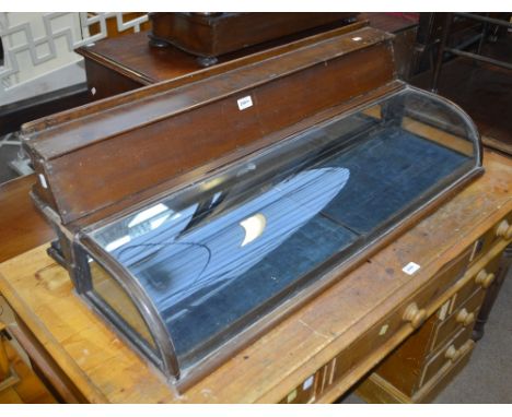 A vintage display case with curved glass front and glass sides, containing two display trays with raised top forming an exter