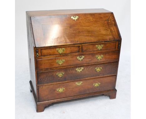 A late George III oak bureau, the fall front enclosing an interior of drawers and pigeonholes above two short and three long 
