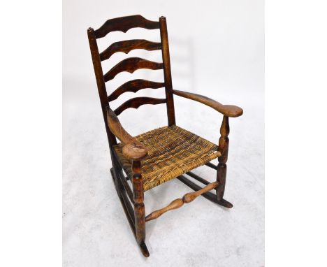 An early 19th century ash and elm shaped ladder back elbow chair with broad swept arms, basketweave seat and turned legs unit