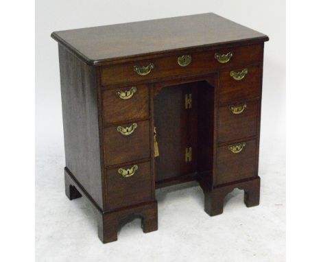 A George II mahogany kneehole desk, the rounded moulded top above frieze drawer, recessed cupboard door and two banks of thre