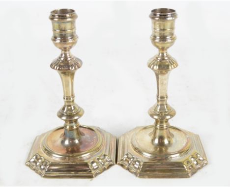 A pair of George II hallmarked silver taper sticks, each turned sconce above octagonal tapering and knopped stem to spreading