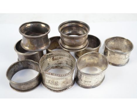 A collection of hallmarked silver napkin rings of various shapes and sizes including a pair of plain form with engine turned 