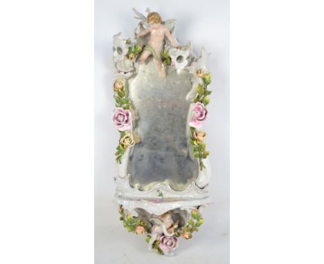An early 20th century Continental porcelain mirror with shaped shelf, floral encrusted frame and set to the upper and lower p