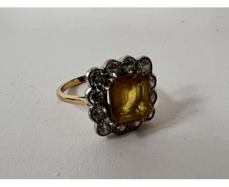 A 1940s 18ct yellow gold ring set with a central emerald cut citrine and flaked by a single row of brilliant cut diamonds. Si