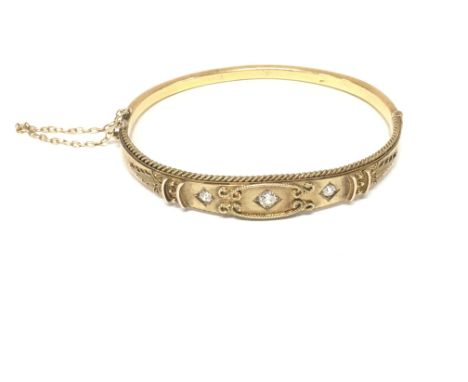 A 15ct gold bangle set with three diamonds. Approx 6cm diameter and 9.79