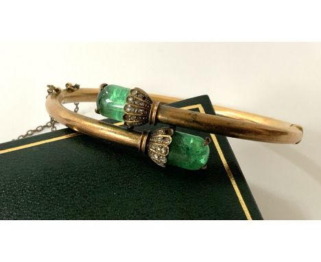 A 14ct gold twist bangle inset with diamond chips and 2 cabochon cut emeralds. 16.3G (Postage A).