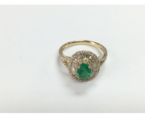 A 14ct gold, oval emerald and diamond double halo ring with split shoulder design. Emerald approx 0.85ct, RBC and baguette di