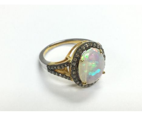 A yellow metal oval opal and diamond cluster ring with diamond set shoulders. Opal approx 1.92ct, diamonds approx 0.38ct, app