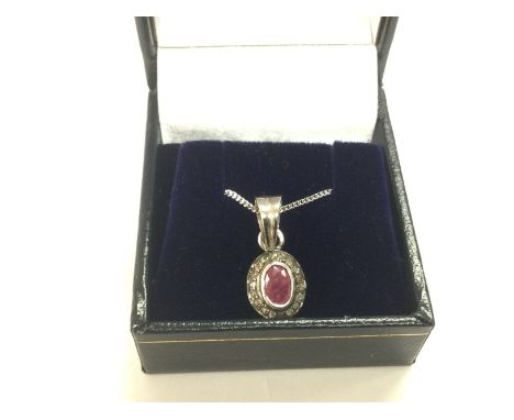 An oval ruby and diamond halo silver pendant on a silver chain. Ruby approx 0.28ct, diamonds approx 0.15ct, approx 3g. Shippi