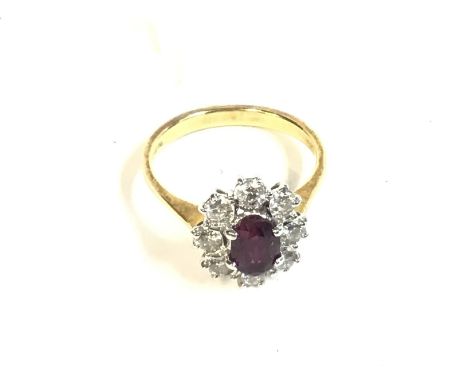 An 18ct gold ring set with central ruby and surrounded by diamonds. size K and 2.96g. Postage A