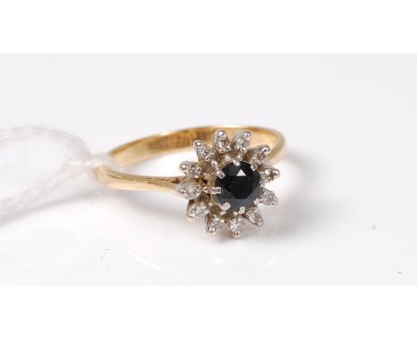 A sapphire and diamond cluster ring, the round sapphire surronded by small round brilliant cut diamonds, total estimated appr