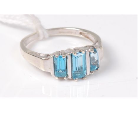 A 9ct white gold three stone topaz ring, the three graduated step cut topaz, all set in white gold with plain band stamped wi