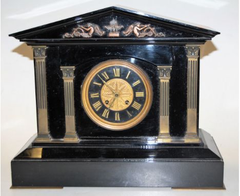 A late Victorian black slate mantel clock of architectural form having a matt black dial with gilt Roman numerals and eight d