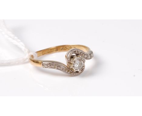 An 18ct and platinum diamond ring, the single round brilliant cut diamond, estimated approx. 0.20cts, set to either side with