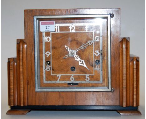 An Art Deco walnut cased mantel clock having silvered Arabic numerals, the eight day movement striking on a gong