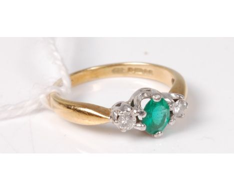 An 18ct green hardstone and diamond ring, the oval green hardstone set to either side with a small round brilliant cut diamon