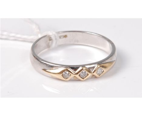 A 9ct three stone diamond ring, the three small round diamonds in a decorative yellow metal mount to a plain white metal band