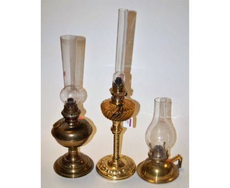 An early 20th century brass pedestal oil lamp having a smoky glass reservoir together with two others