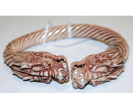 A Chinese white metal bangle, each terminal in the form of a dragons head