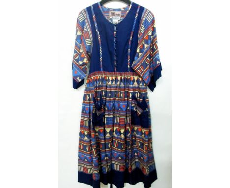 An Origin dress, fabric by Liberty of London, blue, red and cream geometric pattern, full bell sleeves and round button and l