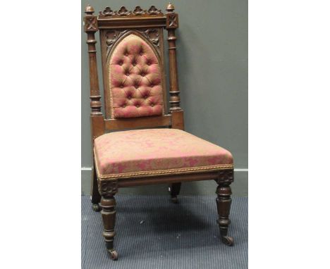 A Gothic style carved oak chair, on carved and turned legs with pink button upholstered seat and back