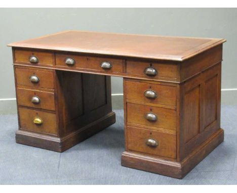 A panelled oak twin pedestal desk of nine drawers on a plinth base, 77 x 138 x 76cm