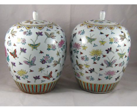 A pair of Chinese ceramic jars and covers, the white body with overglaze enamelled butterflies and flowerheads, with hardwood