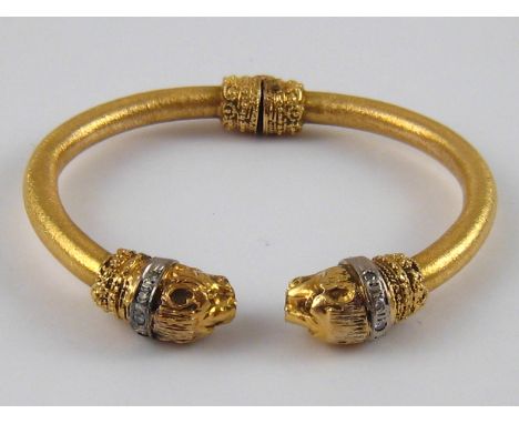 A yellow metal (tests 18 carat gold) bangle (with metal spring), designed as two lions with diamond set collars, approx. 58mm