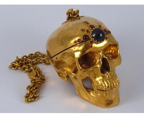 A gold plated hinged brass skull box on heavy chain with cabochons on the forehead. 10x6x10cm. 