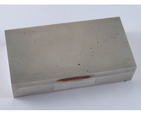 A silver cigarette box with engine turned finish, yellow metal thumbpiece and unwritten cartouche, Birmingham, 1964. 17x9x3.5