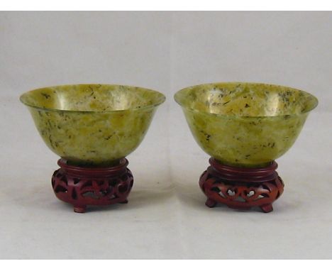 A pair of Chinese turned jade bowls, 10cm. diameter, on hardwood stands. 