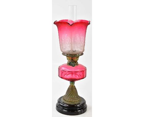 A late Victorian oil lamp, the faceted cranberry and frosted glass shade etched with roses and scrolling detail above the fac