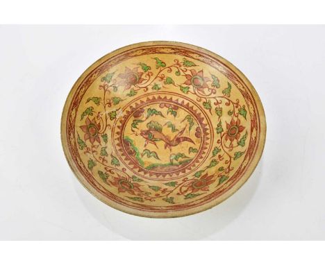 A 17th/18th century Chinese terracotta ground bowl painted with a central panel of a fish within a foliate scroll border, dia
